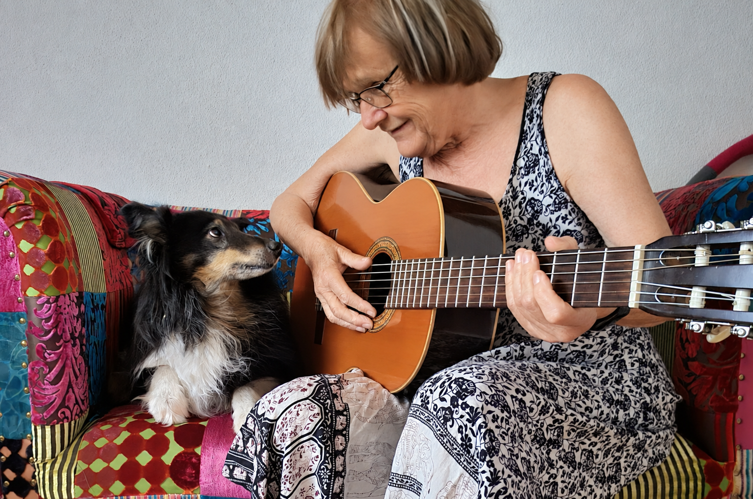 Iris Minder spielt Gitarre, neben ihr sitzt ihr Hund.